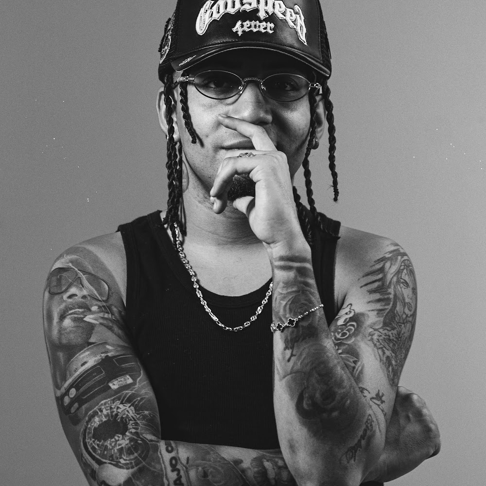 Retrato de Andy Alaska con gorra, gafas y brazos tatuados
